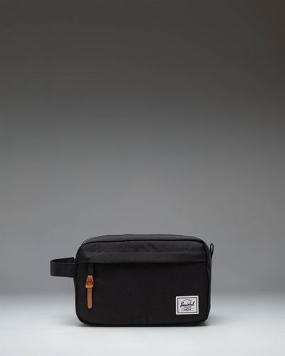 Herschel Supply Co. Chapter Travel Kit in black, showing the clean exterior design, side handle, and front zippered pocket.