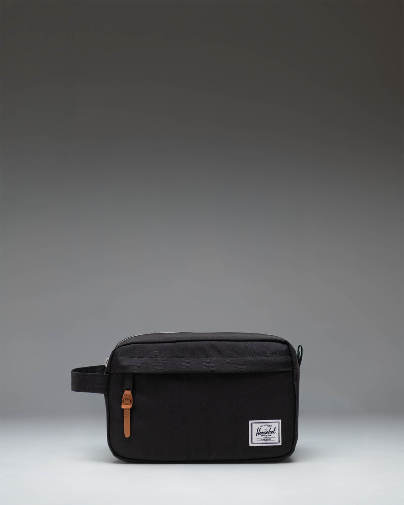 Herschel Supply Co. Chapter Travel Kit in black, showing the clean exterior design, side handle, and front zippered pocket.