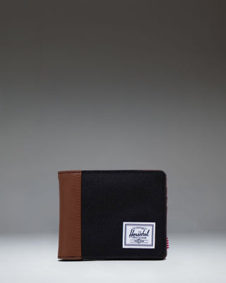 Herschel Supply Co. Hank Wallet in Black/Tan shown opened, displaying the interior card slots and a clear ID window.