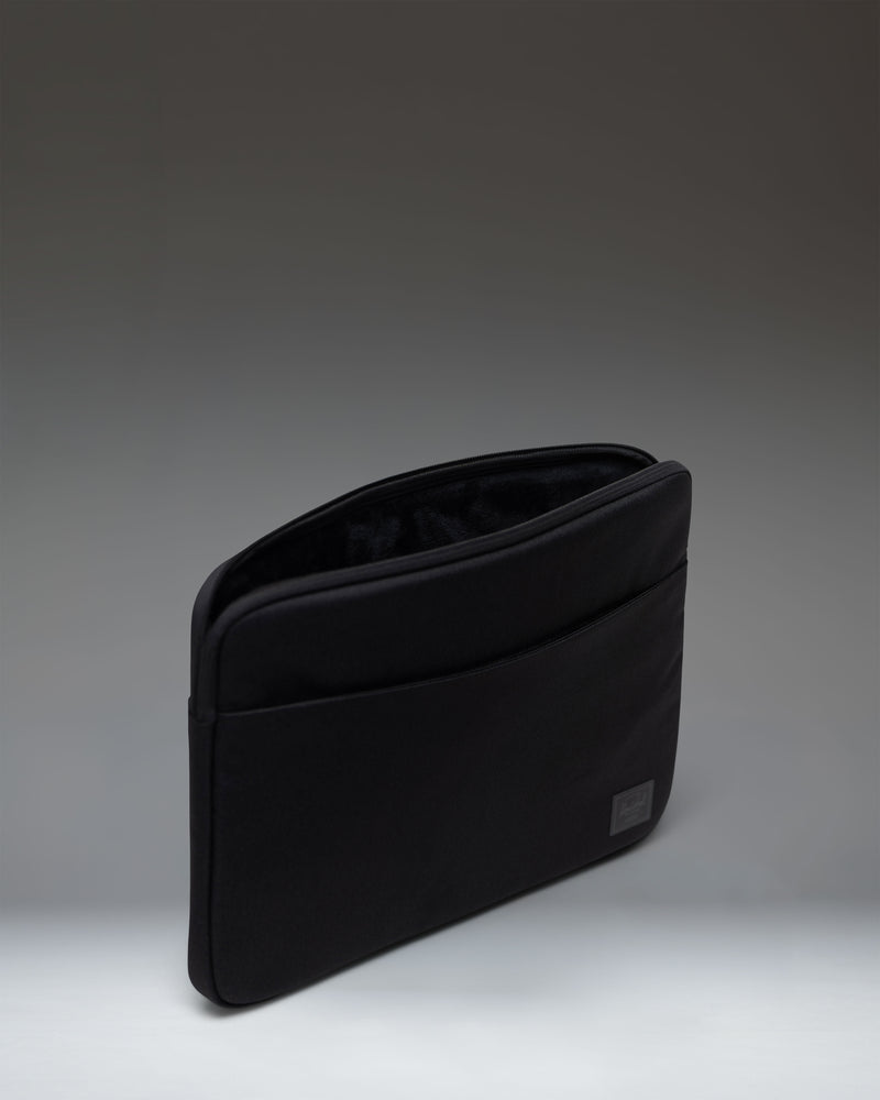 Black Herschel Supply Co. Denman 15-16 Inch Sleeve Tech laptop case shown from a side view, highlighting its slim profile.
