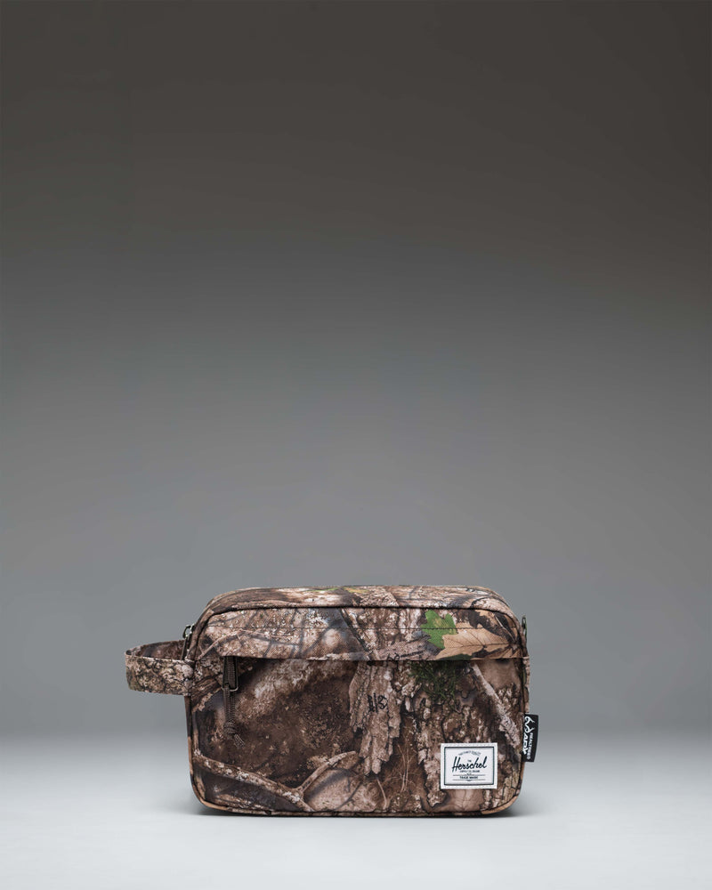 Herschel Supply Co. Realtree Chapter Travel Kit in Realtree APX Camo pattern, featuring a side handle and front zippered pocket.