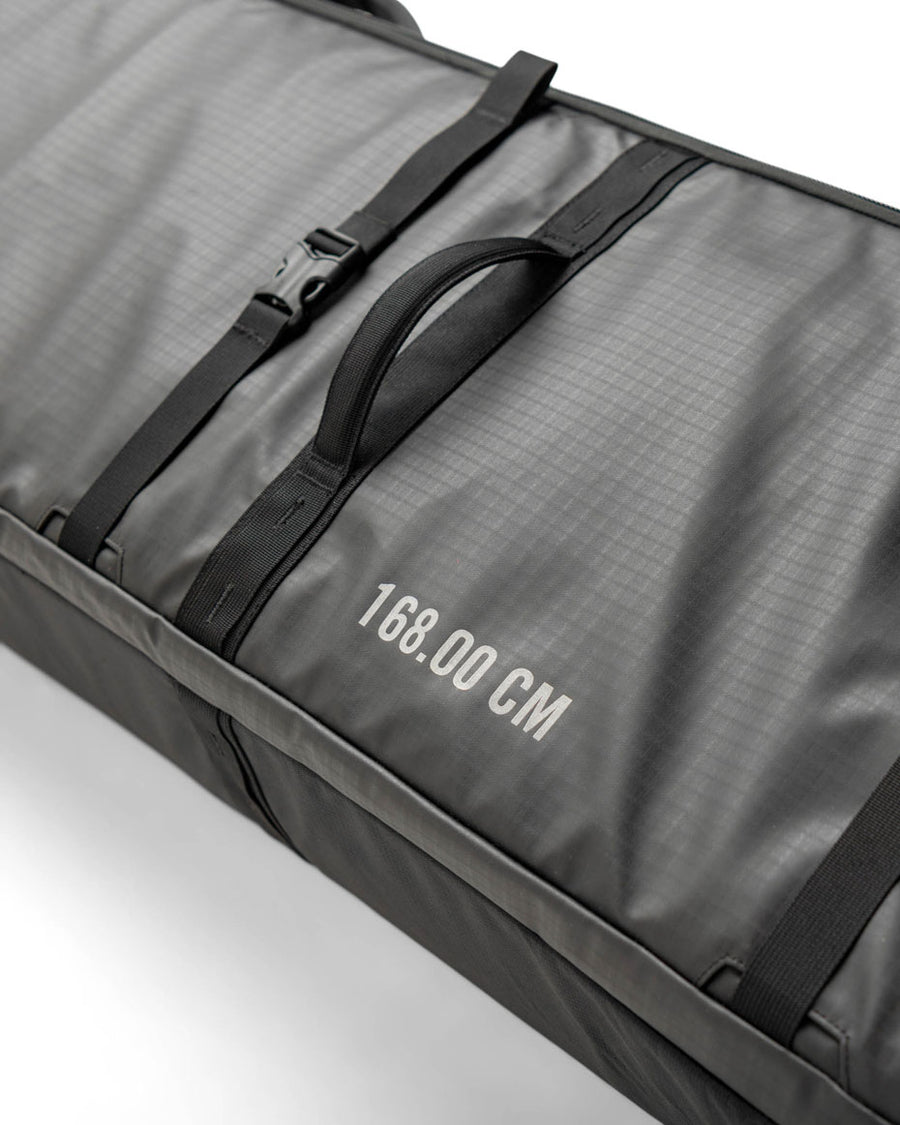 Black Herschel Supply Co. Snow Roller Bag (188cm) shown fully packed with snowboard gear, jackets, and winter sports equipment.