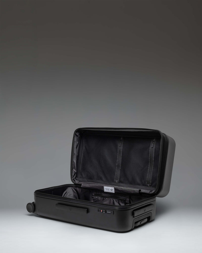 Black Herschel Heritage Hardshell Medium Luggage Exp, showing its durable textured exterior and classic design.