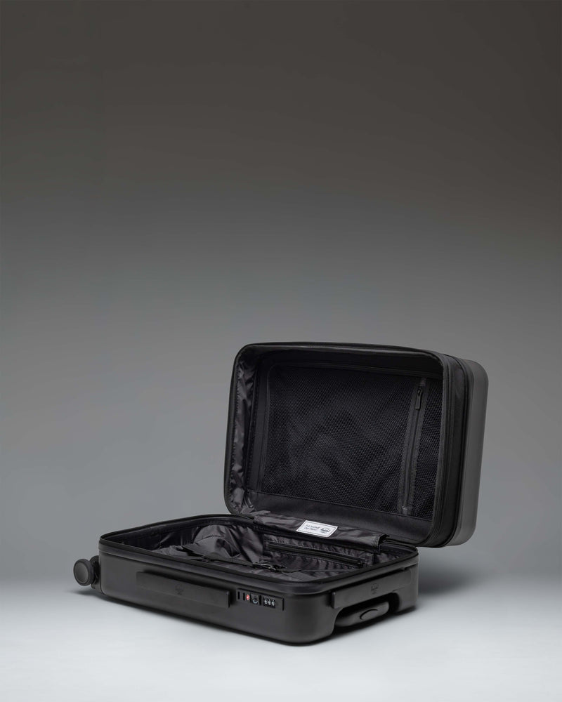Herschel Heritage Hardshell Large Carry On Exp suitcase in Black, showing the back view with telescopic handle and wheels.