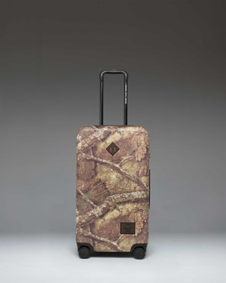 Realtree Herschel Heritage Medium Luggage in Realtree APX Camo pattern, a rolling suitcase featuring a distinct woodland camouflage design.