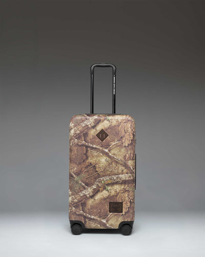 Realtree Herschel Heritage Medium Luggage in Realtree APX Camo pattern, a rolling suitcase featuring a distinct woodland camouflage design.