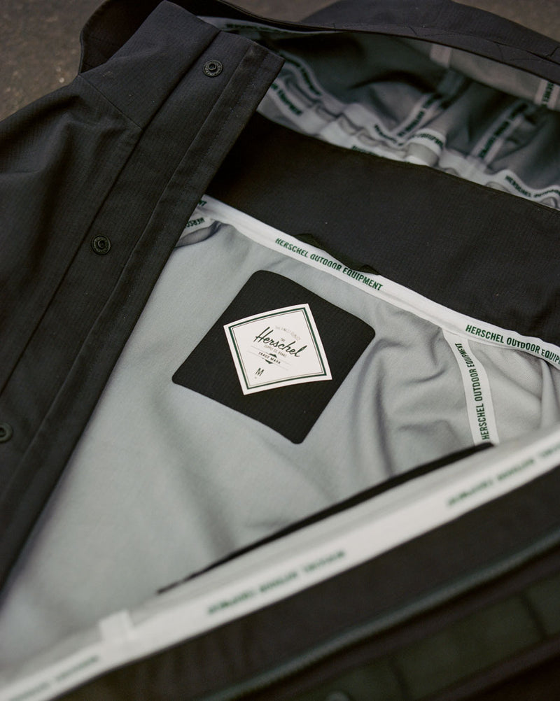 Men's Herschel Supply Co 3-Layer Shell Jacket in black, showing the fabric, fit, and design details from a specific angle.