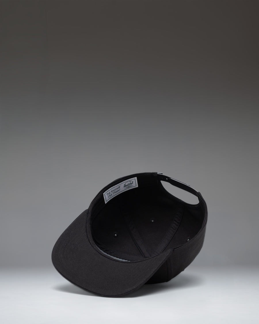 Herschel Supply Co Whaler 6 Panel Cap in black, featuring a structured crown, flat brim, and an adjustable strapback closure.