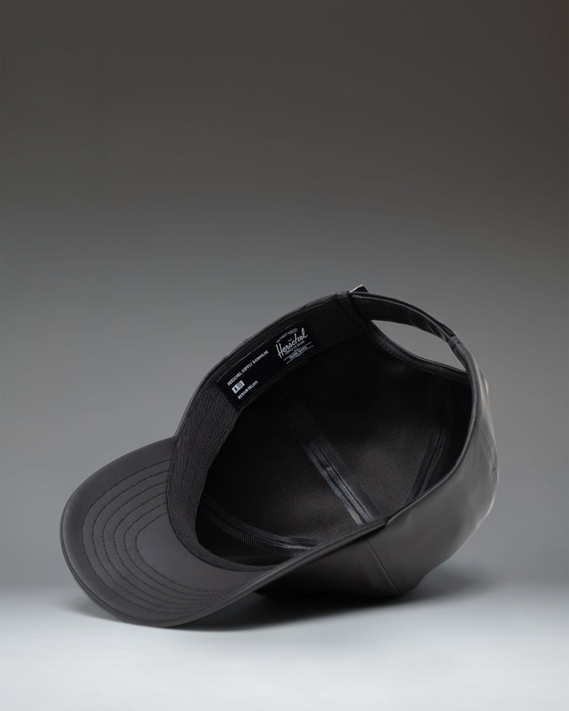 Herschel Supply Co. Sylas Rain Cap in black, featuring a classic six-panel design with an adjustable strap back.