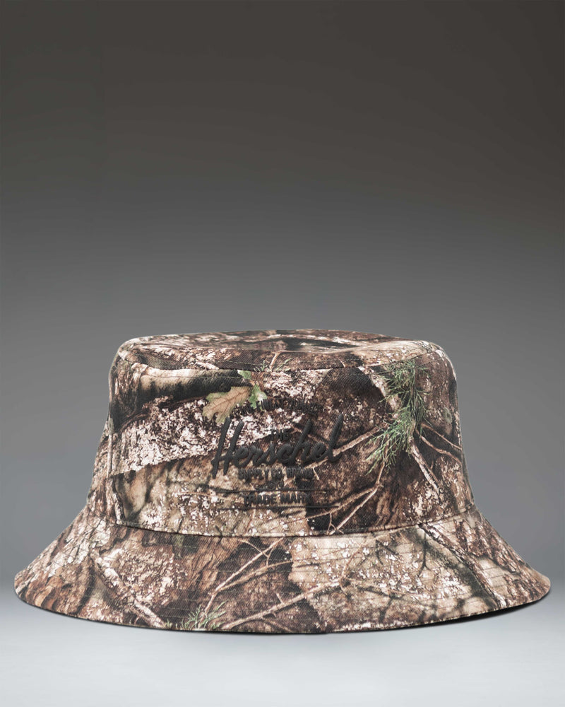 Herschel Supply Co. Realtree Norman Bucket Hat in Realtree APX Camo, showing the full hat with its camouflage pattern and stitched brim.