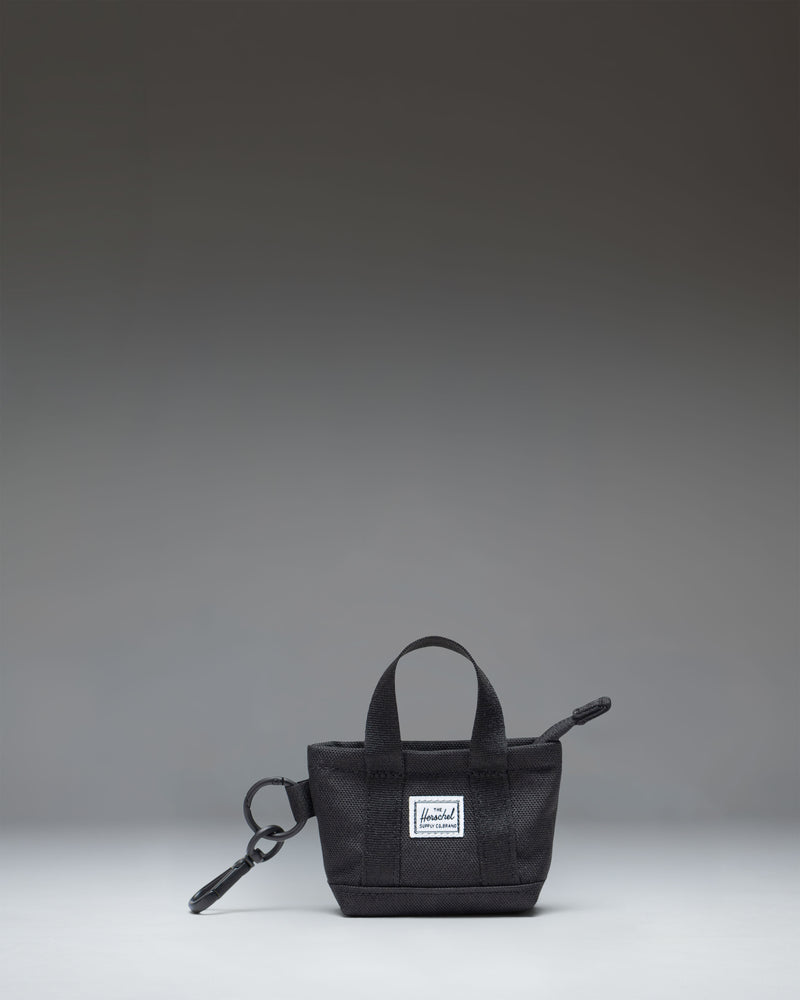 Herschel Supply Co. Heritage Tote Bag Charm in black, featuring a mini zippered tote design with a metal keyring and clip attachment.