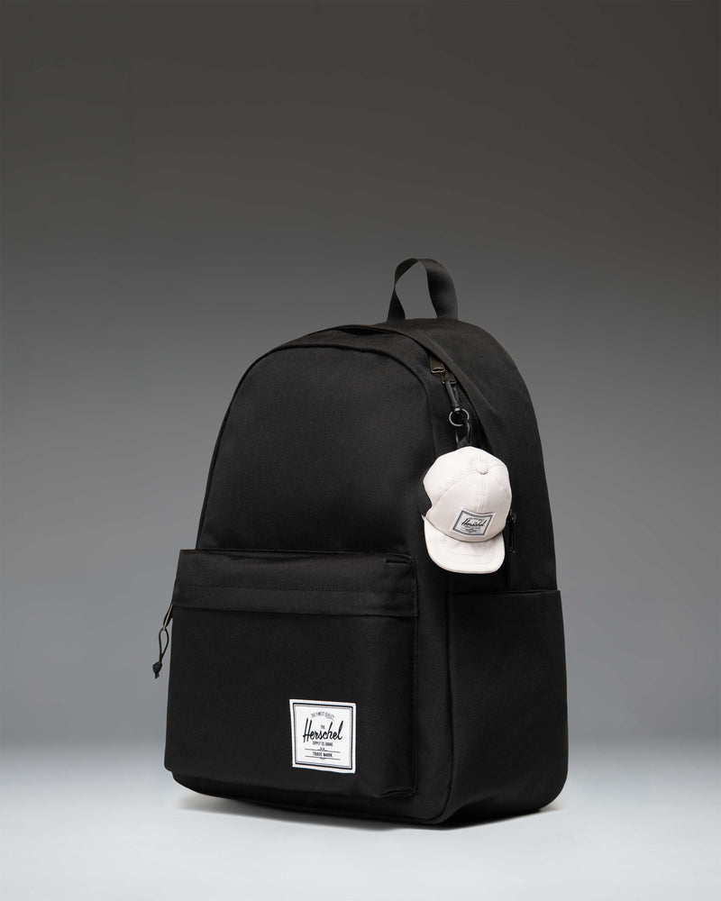 Herschel Supply Co. Sylas Classic Cap Bag Charm in Moonbeam beige, featuring a miniature baseball cap design with an attached metal clip.