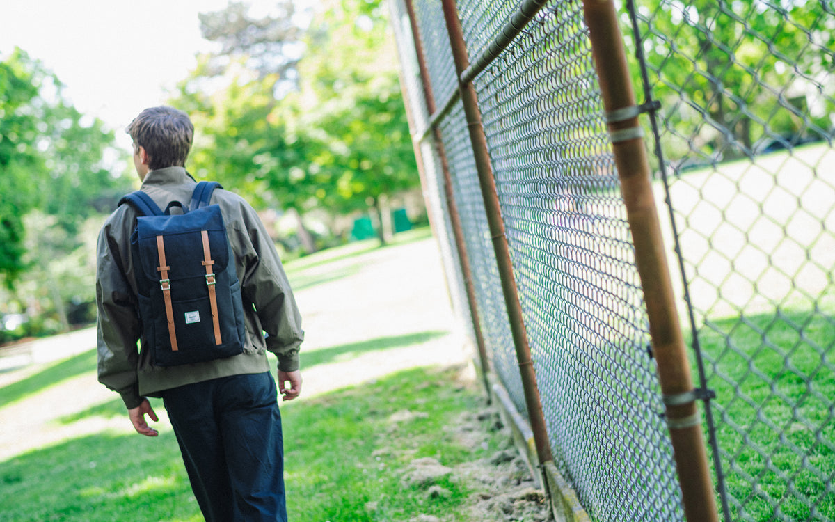 Herschel Supply Co. Retreat Backpack in classic black, showing the front view with dual magnetic strap closures and woven logo label.