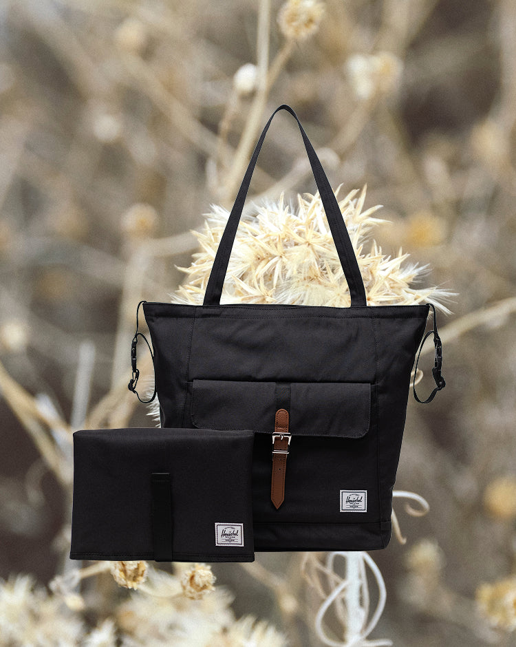 Herschel Retreat Tote Diaper Bag in black. Front view of the tote showing the clean design, shoulder straps, and iconic woven label.