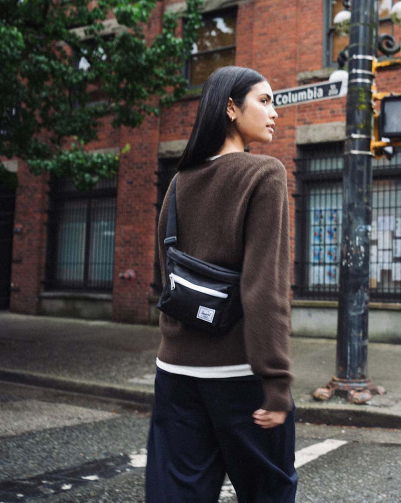 Herschel Supply Co. Pop Quiz Hip Pack in black, featuring a sleek, minimalist design with a front zippered pocket and adjustable strap.