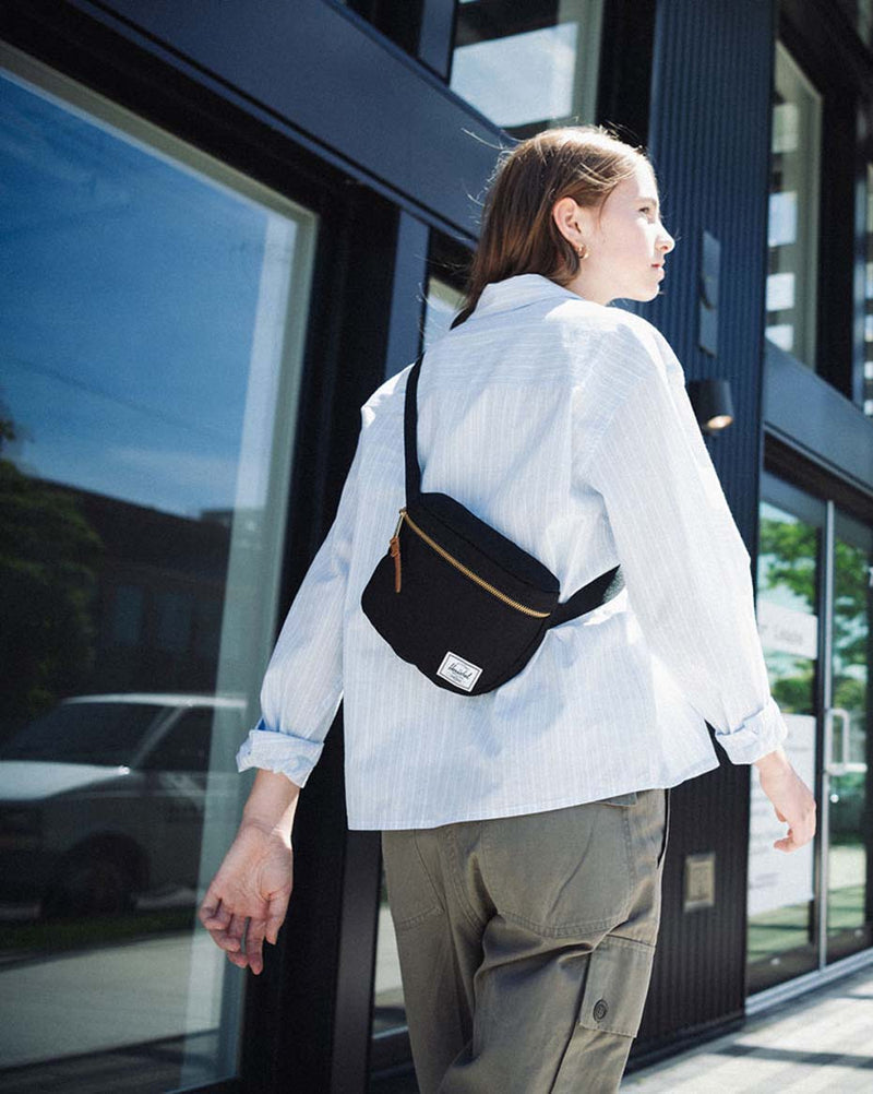 Herschel Supply Co. Settlement Hip Pack in solid black, showing a sleek, minimalist design with a zippered main compartment and front pocket.