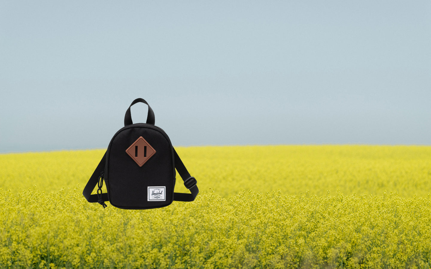 Herschel Heritage Crossbody Little Herschel in black shown from a front lifestyle angle against a neutral background.