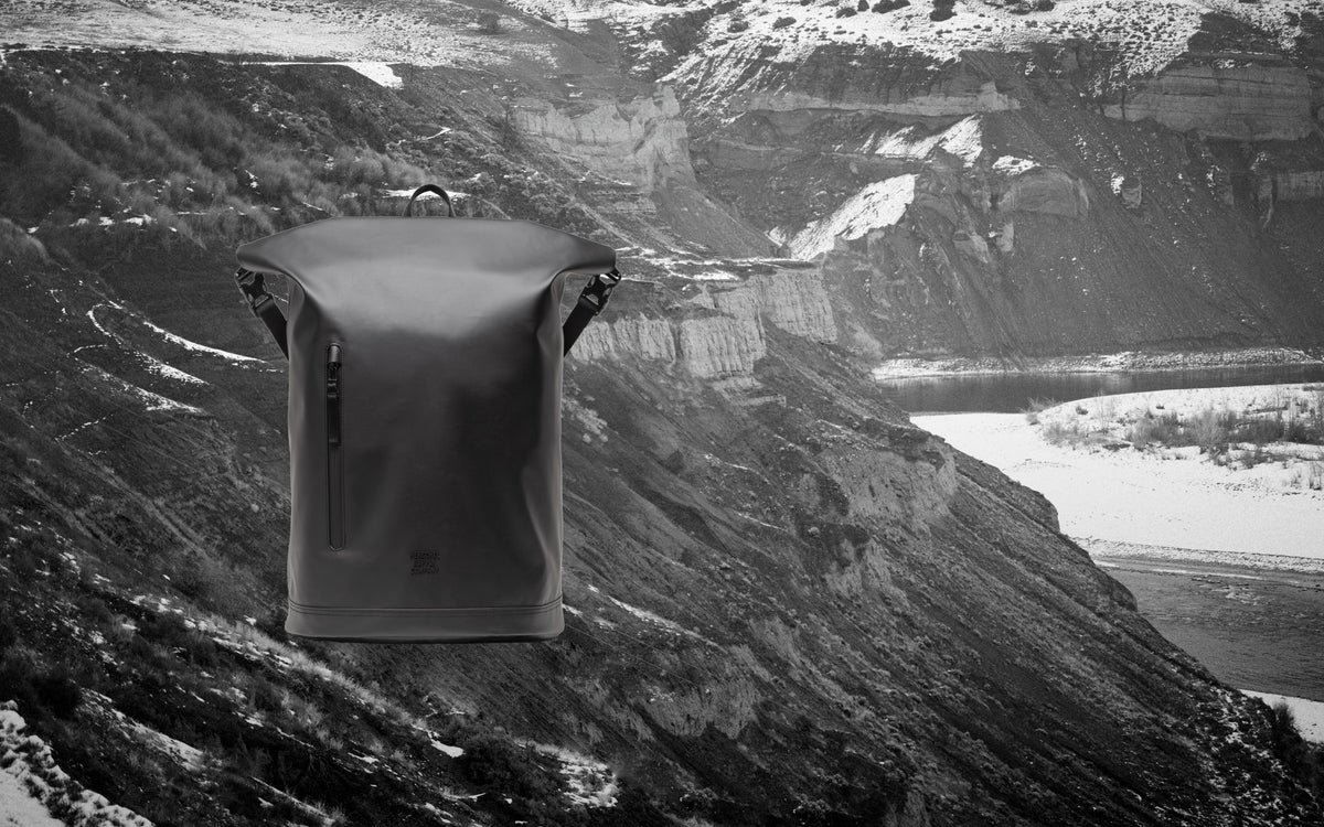 Herschel Supply Co. Roll Top Backpack in Black shown from the front on a desktop view.