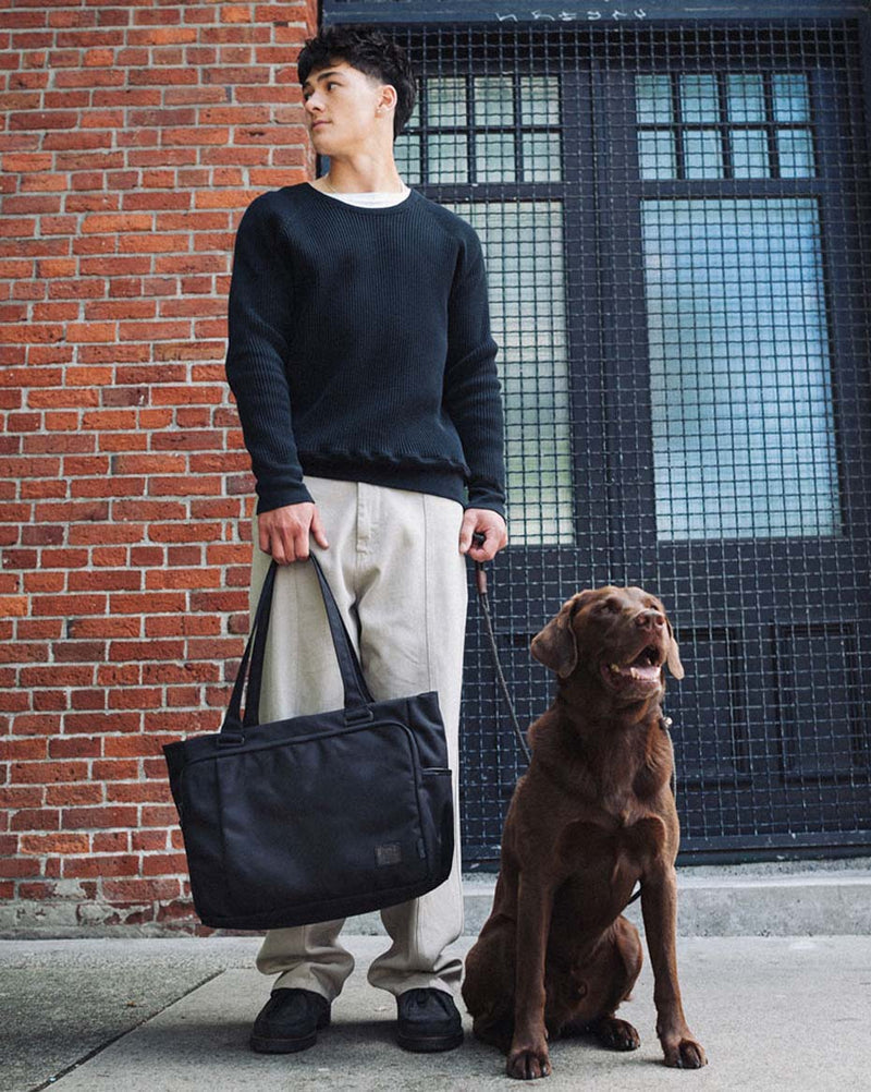 Black Herschel Supply Co. Kaslo Tote Tech Cordura bag featuring top carrying handles, a zipper closure, and a front pocket.