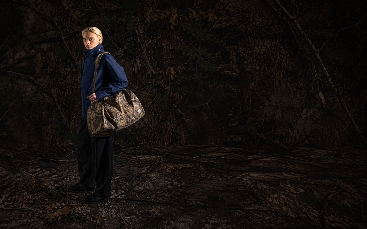 Herschel Supply Co. Realtree Novel Duffle bag in Realtree APX Camo pattern shown from a front angle on a plain background.