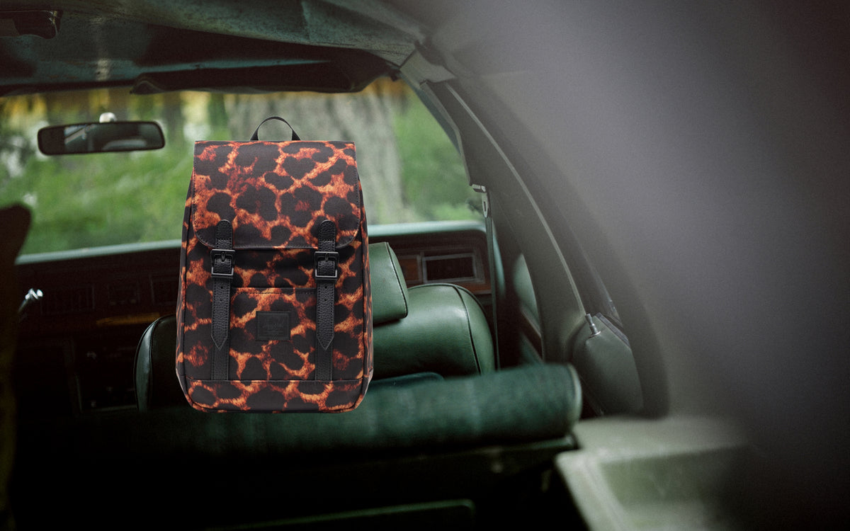 Herschel Retreat Mini Backpack in Digi Leopard print, featuring a classic cinch top design and front straps on a lifestyle desktop banner.