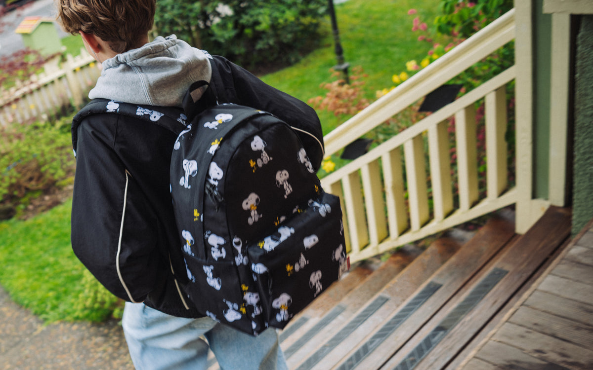 Herschel Supply Co. Peanuts Classic XL Backpack in Snoopy and Woodstock Black pattern shown on a desktop banner.