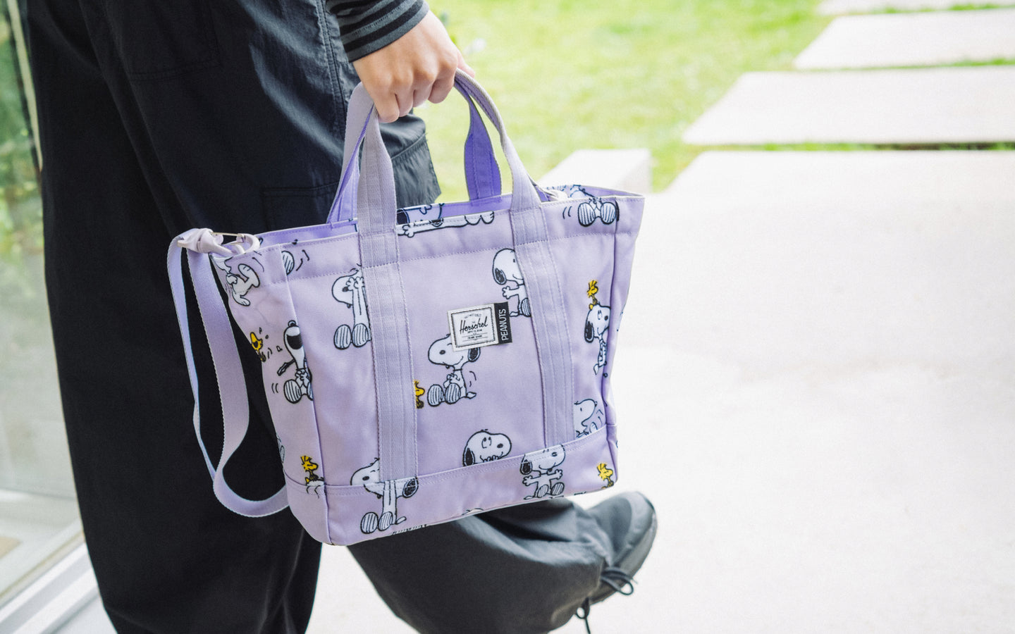 Herschel Heritage Small Tote in Snoopy and Woodstock Pastel Lilac, shown from the front against a plain background.