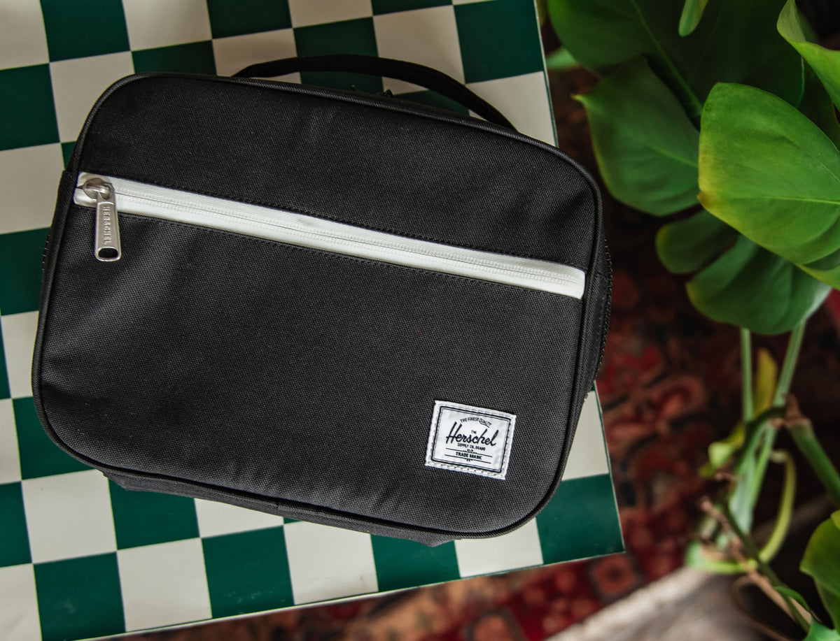Herschel Supply Co. Pop Quiz Lunch Box Little Herschel in black, featuring a clean front view highlighting its classic, durable design.