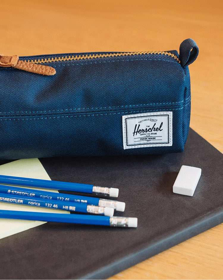 Herschel Supply Co. Settlement Pencil Case in solid navy blue featuring a exposed zipper and a woven brand label on the front.