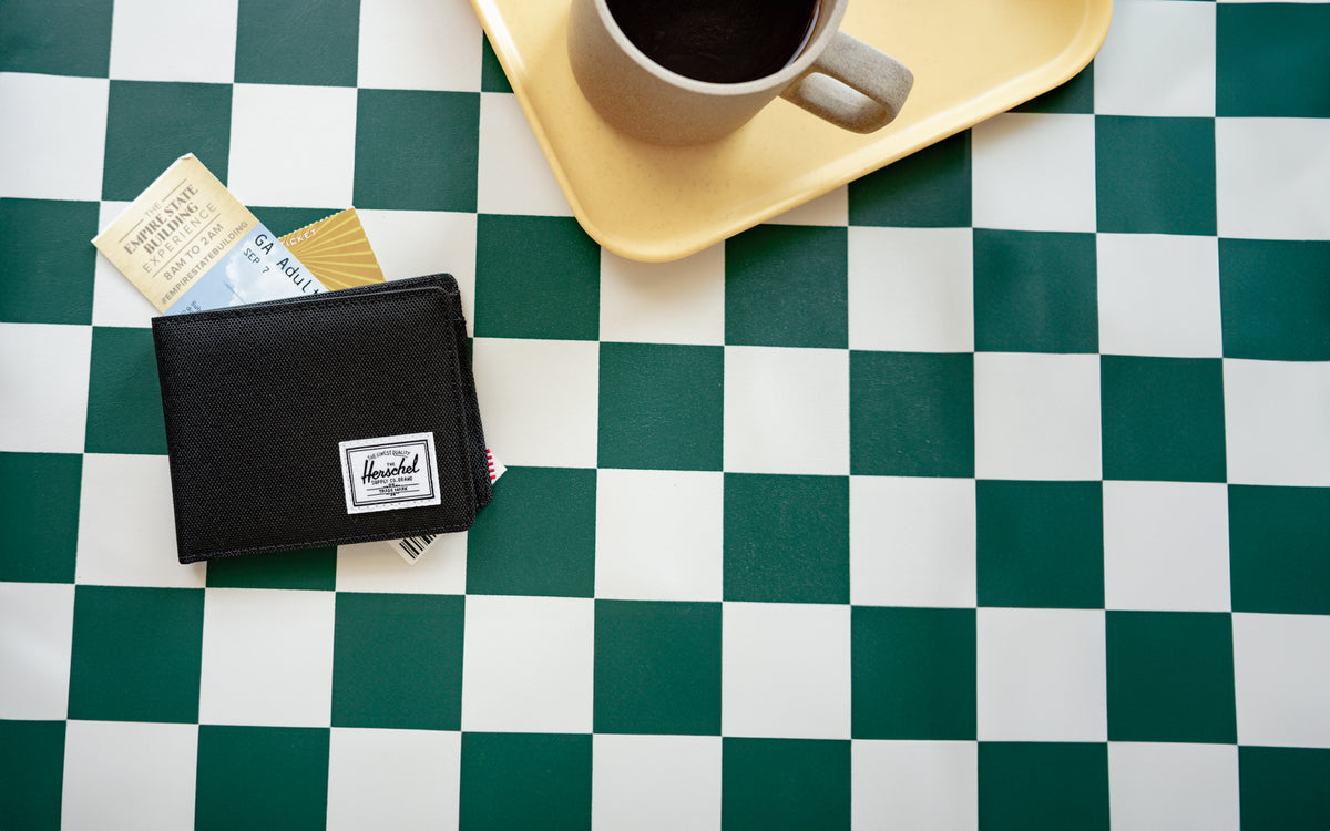 Herschel Supply Co. Roy Coin Wallet in black, showcasing its classic bi-fold design and signature woven label.