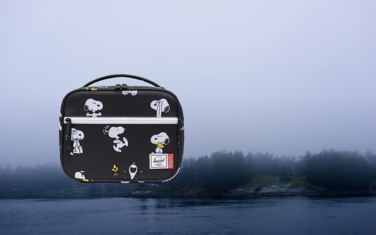 Herschel Supply Co. Peanuts Pop Quiz Lunch Box in Snoopy and Woodstock Black featuring a Snoopy patch on a black background.