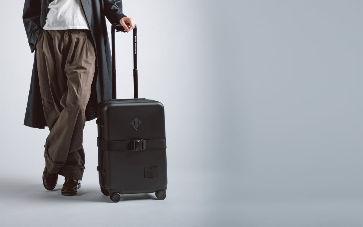 Herschel Heritage Hardshell Large Carry On Expandable luggage in black, showcasing a durable textured exterior and sleek telescoping handle.