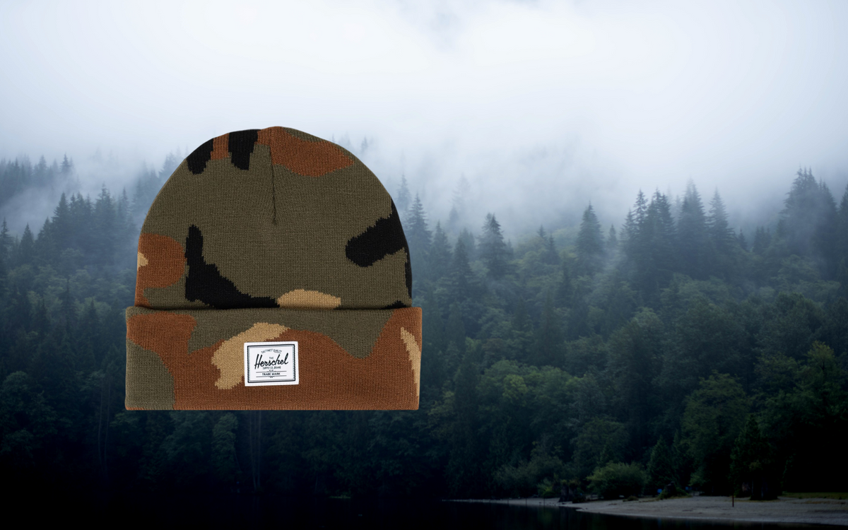 Herschel Supply Co. Elmer Camo Beanie in Woodland Camo patterned knit fabric with a folded cuff and a classic woven logo label on the front.