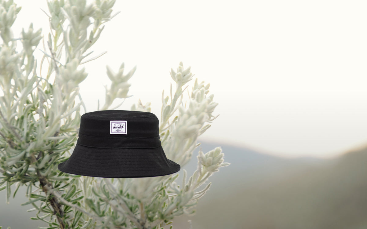 Herschel Supply Co. Baby Bucket Hat for ages 6-18 months in solid black, viewed from the front on a desktop-optimized hero layout.