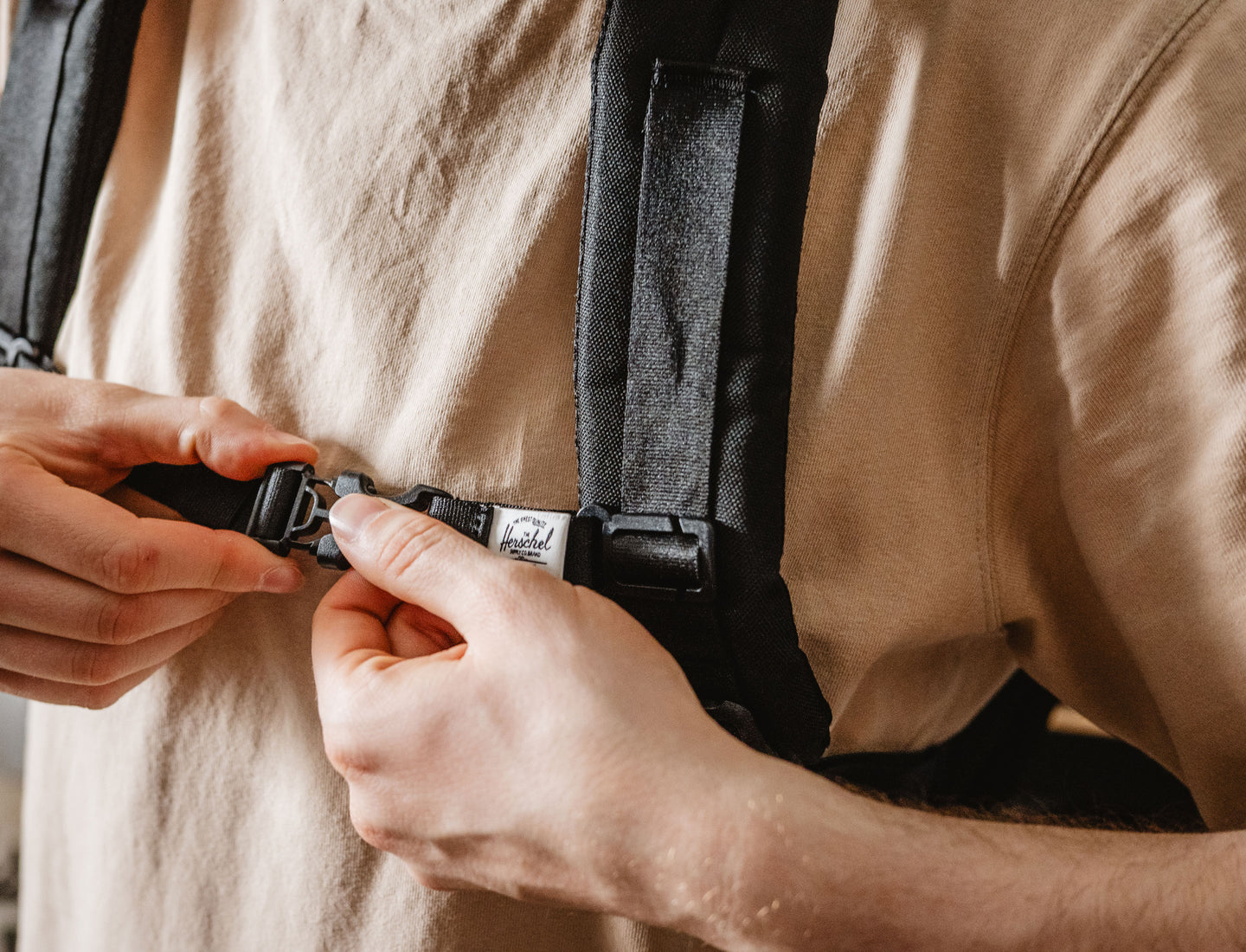 Black adjustable Herschel Supply Co. sternum strap accessory designed for backpacks, shown on a clean background.