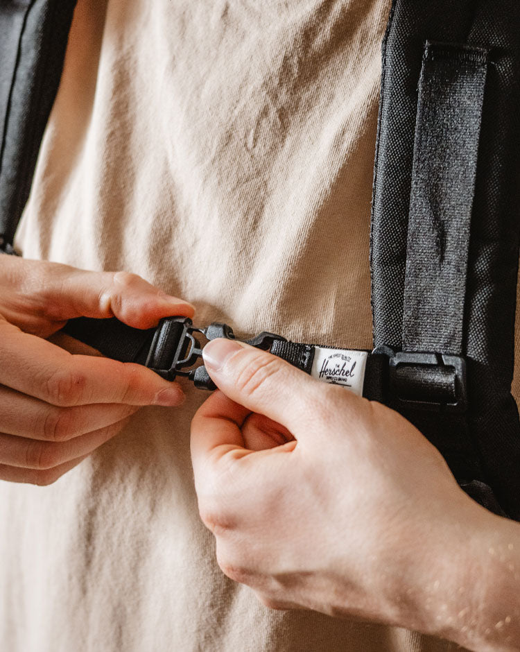 Herschel Supply Co. black sternum strap designed to attach to backpack shoulder straps for extra support.