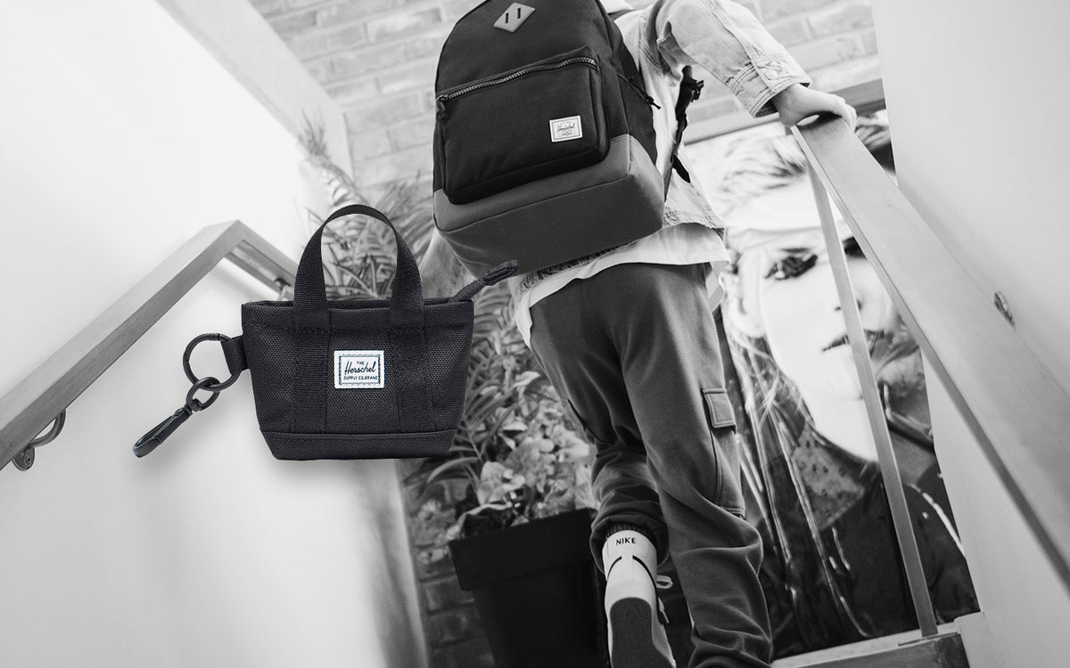 Herschel Supply Co. Heritage Tote Bag Charm in black, designed as a miniature version of the classic tote bag with a zipper enclosure.