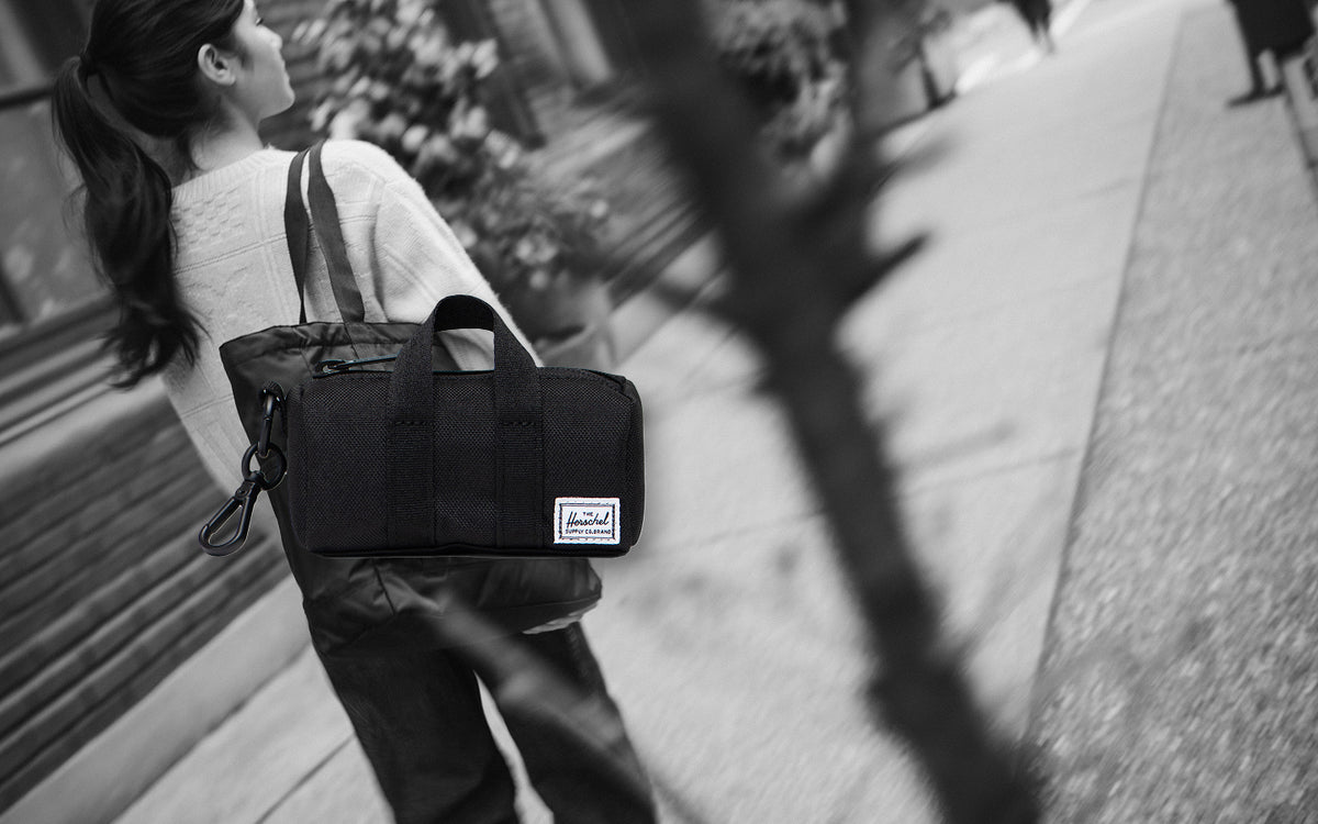 Herschel Novel Duffle Bag Charm in black, a miniature version of the classic duffle bag designed as a stylish accessory or keychain.