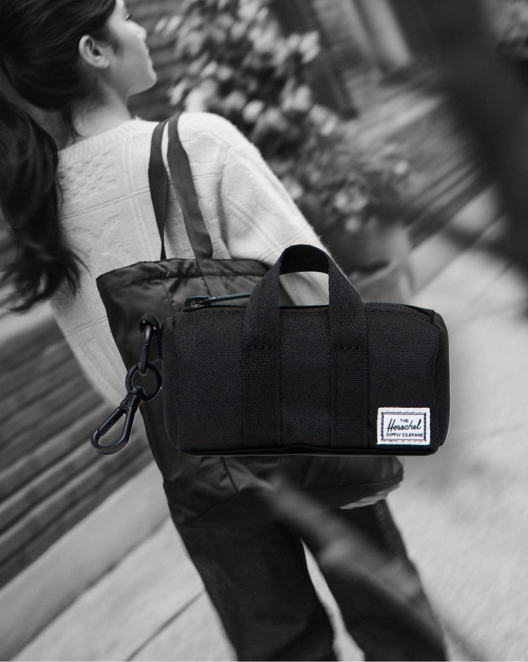 Herschel Novel Duffle Bag Charm in black, a miniature version of the classic duffle bag designed as a stylish accessory or keychain.
