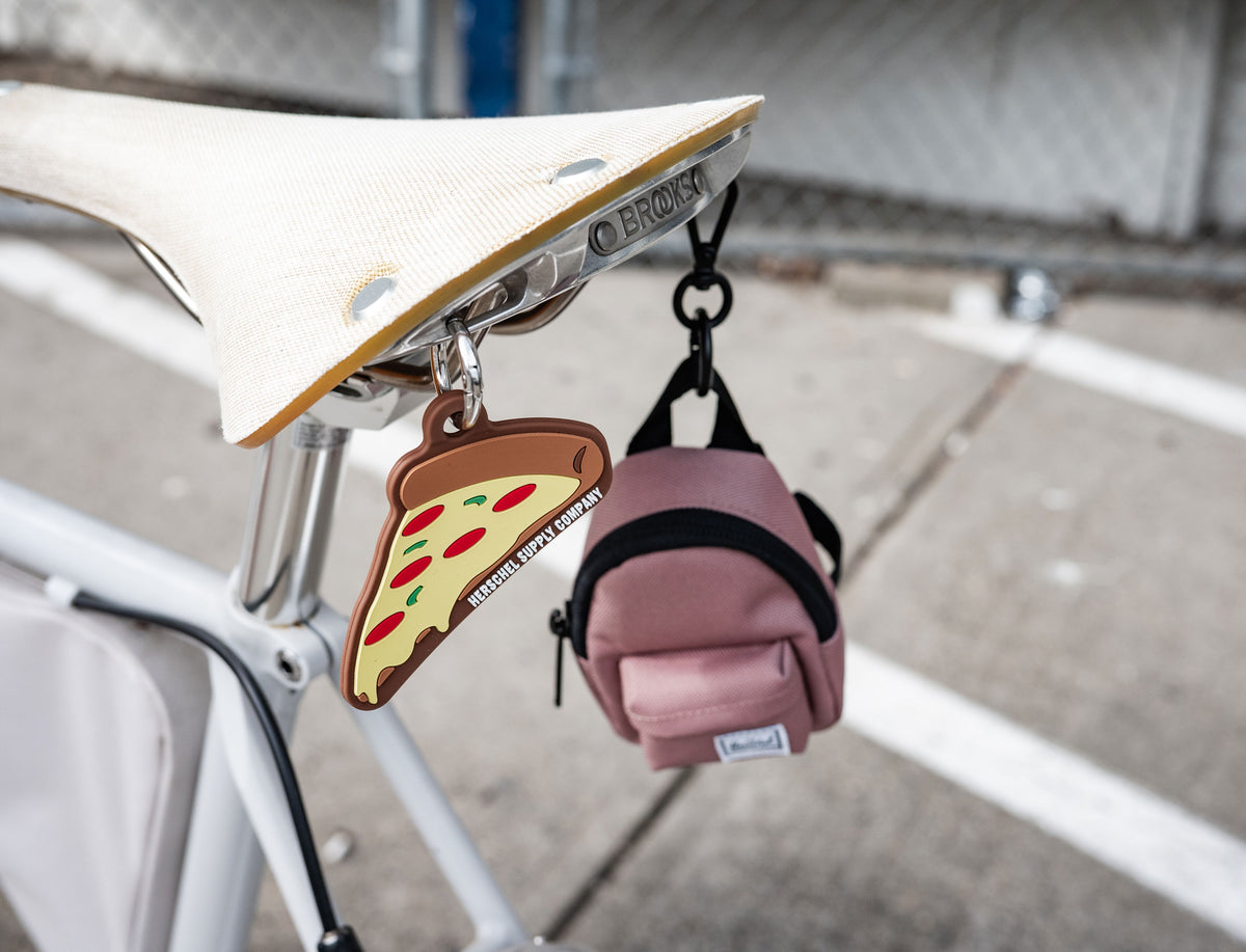 Herschel Supply Co. Pepperoni Pizza silicone bag charm featuring a metal keyring attached to a Herschel backpack.