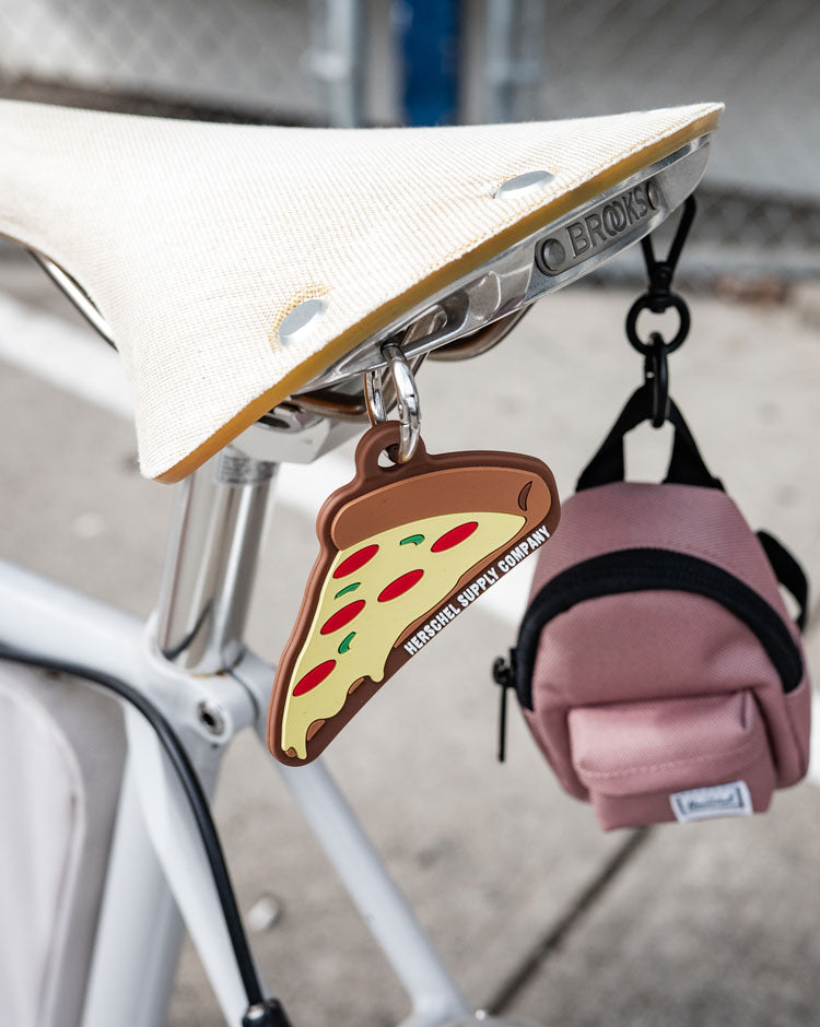 Herschel Supply Co. Pepperoni Pizza Bag Charm shaped like a slice of pizza with a metal keyring attachment.
